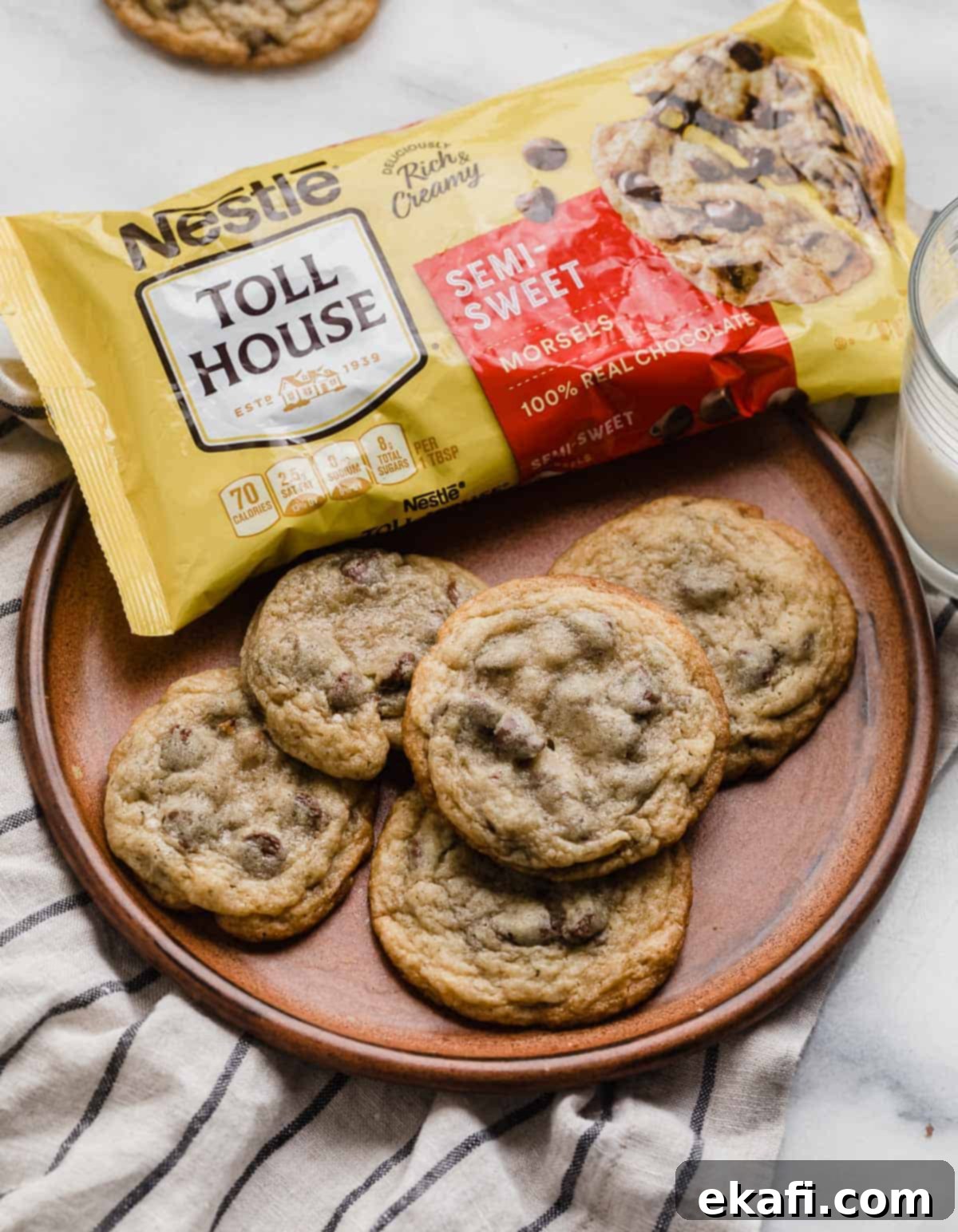 Nestle Toll House Signature Chocolate Chip Cookies 2 Nestle Toll House Chocolate Chip Cookies on a brown plate with a bag of Nestle chocolate chips in the background, evoking a sense of classic homemade baking.