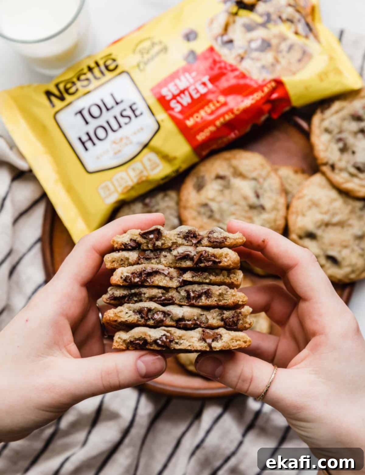 Nestle Toll House Signature Chocolate Chip Cookies 6 A hand gracefully holding a stack of perfectly baked Nestle Toll House Chocolate Chip Cookies, each cut in half to reveal their chewy centers and an abundance of melty chocolate chips.