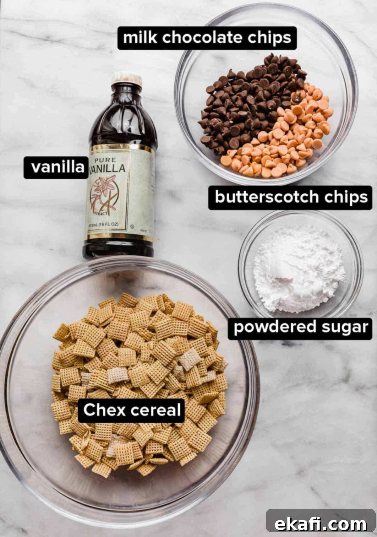Butterscotch Cloud Crunch 3 A flat lay of all the ingredients needed for Butterscotch Puppy Chow on a white marble surface. The components include golden Chex cereal, a pile of white powdered sugar, dark milk chocolate chips, amber butterscotch chips, and a small vial of vanilla extract.