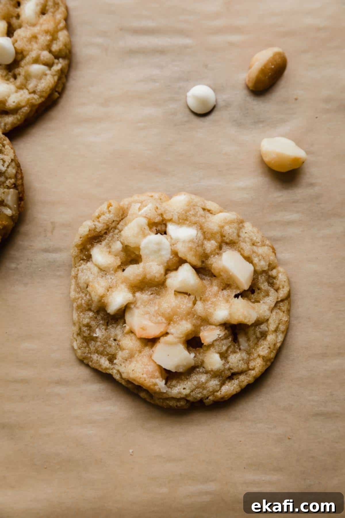 White Chocolate Macadamia Nut Cookies 2 One White Chocolate Macadamia Nut Cookie on a Kraft colored parchment paper.