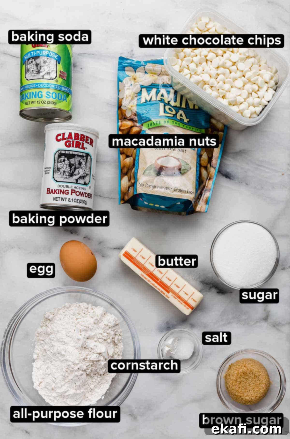 White Chocolate Macadamia Nut Cookies 3 White Chocolate Macadamia Nut Cookies ingredients on a white marble surface: flour, butter, baking powder and soda, cornstarch, salt, sugar, egg, white chocolate chips and salted macadamia nuts.