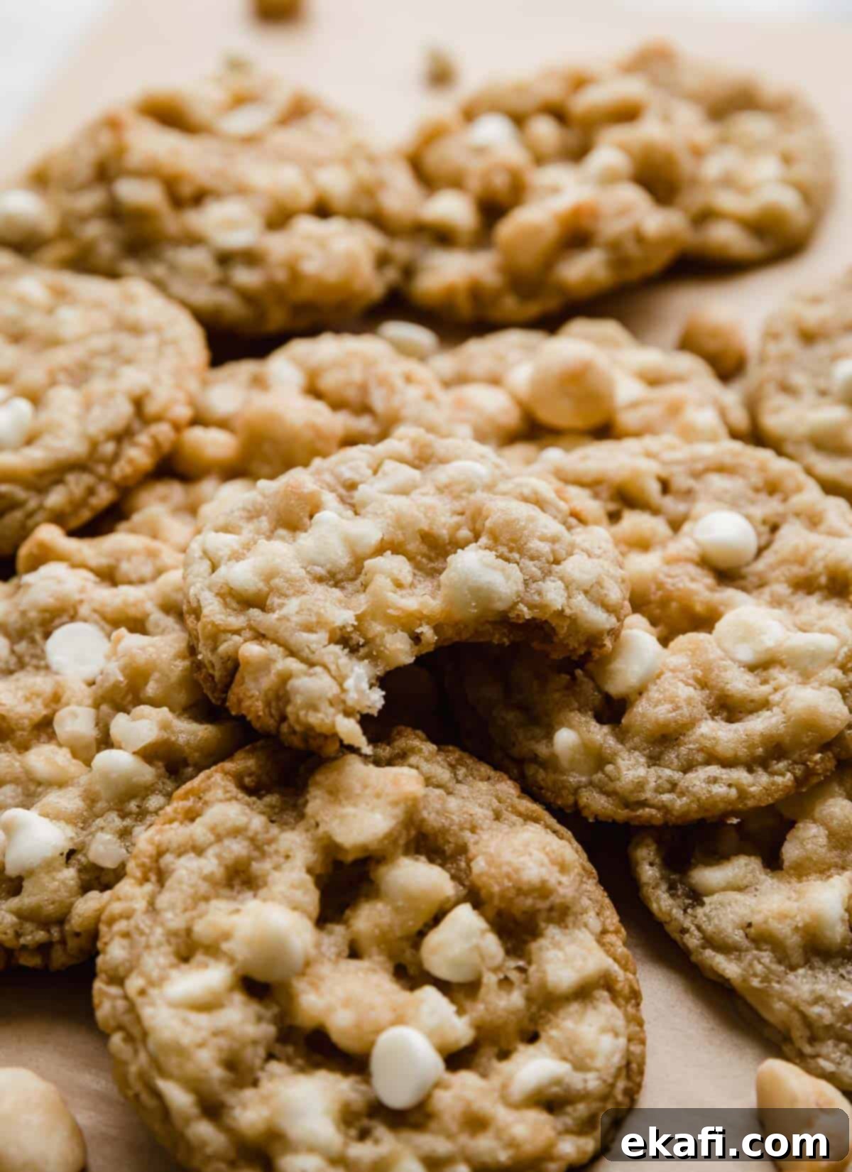 White Chocolate Macadamia Nut Cookies 7 A White Chocolate Macadamia Nut Cookie with a bite taken out of it, stacked on a small pile of other macadamia nut white chocolate chip cookies.
