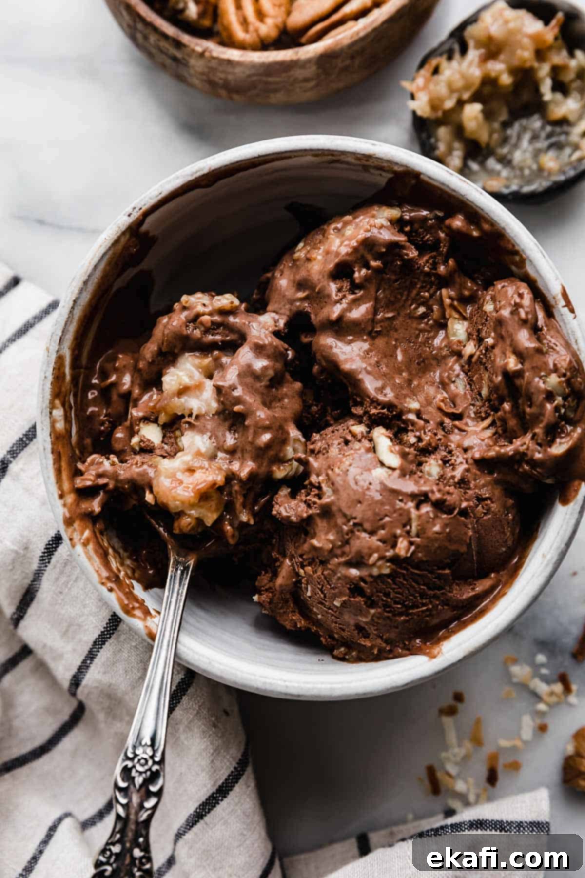 Decadent German Chocolate Ice Cream 9 The best German Chocolate Cake Ice Cream in a white bowl with a spoon scooping out some of the coconut pecan chocolate ice cream.