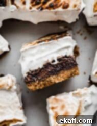 Μπράουνις Φωτιάς 11 S'mores Brownies με μια καβουρδισμένη σπιτική κρέμα marshmallow και βάση μπισκότου graham σε λευκό φόντο.