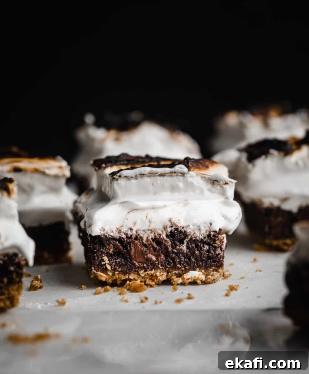 Μπράουνις Φωτιάς 9 Τα καλύτερα S'mores Brownies όλων των εποχών, κομμένα σε τετράγωνα σε λευκή μαρμάρινη επιφάνεια με μαύρο φόντο.