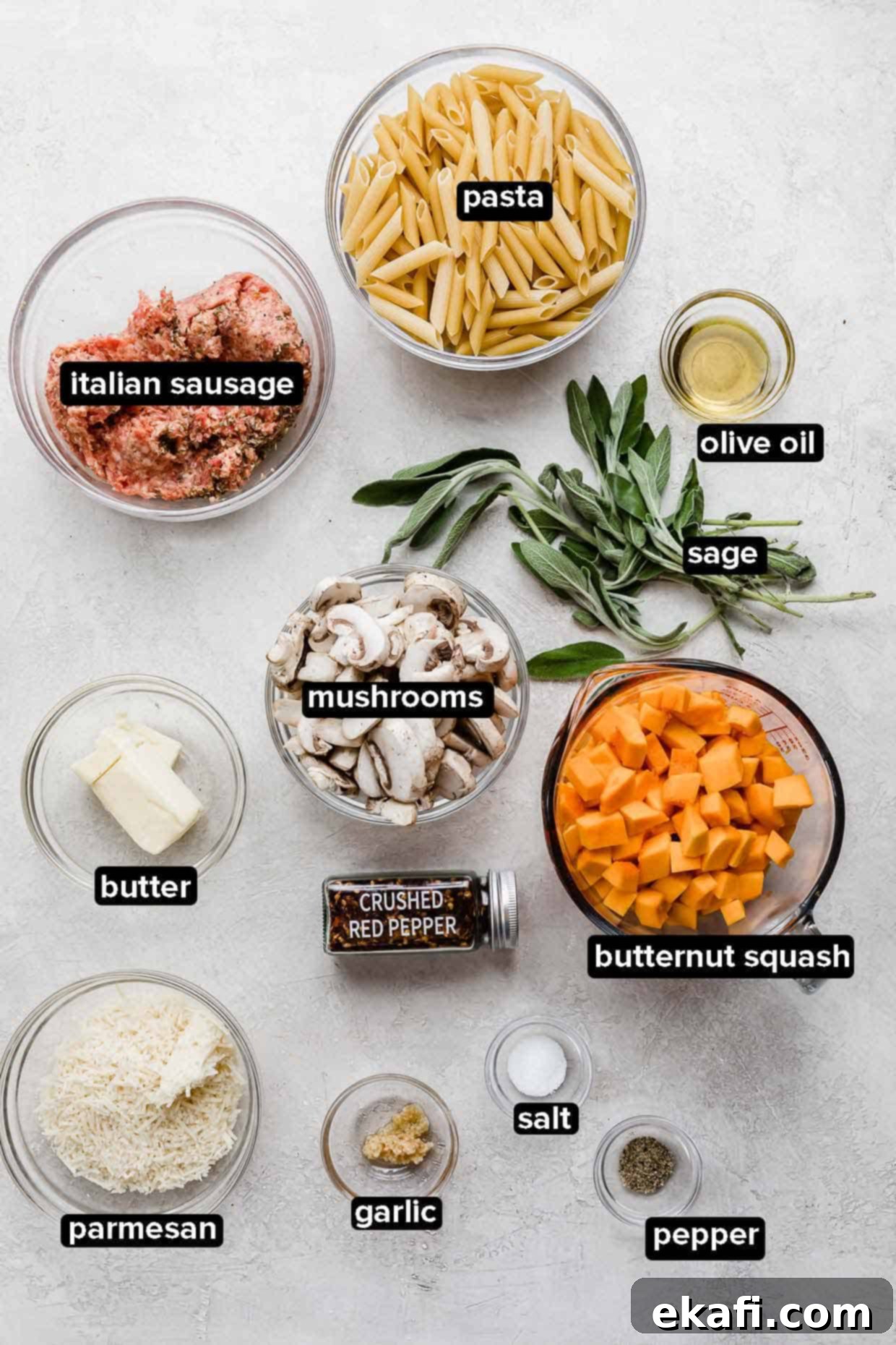 Butternut Squash Sausage Pasta 3 Butternut Squash Mushroom Pasta ingredients on a light gray background, including penne, sausage, squash, mushrooms, sage, and butter.
