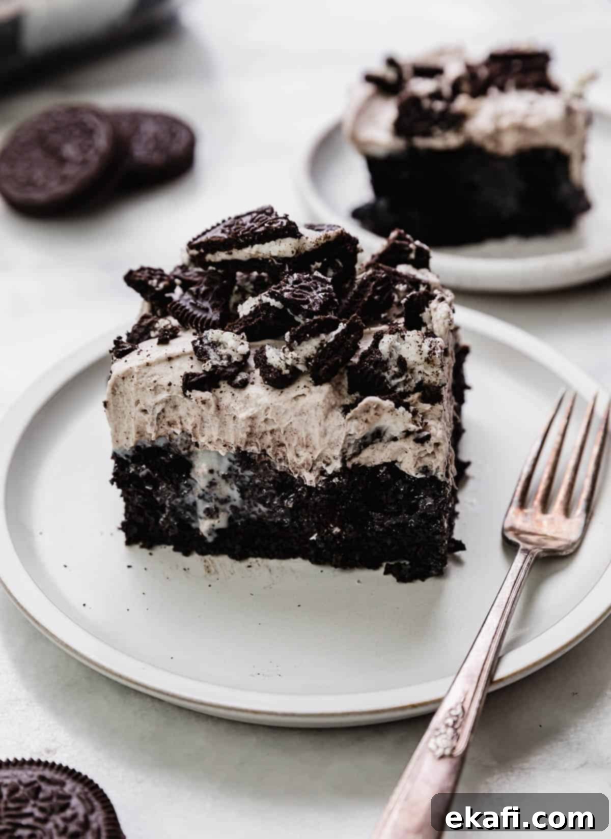 Όρεο Τρυπητό Κέικ 2 Μια τετράγωνη φέτα από Oreo Poke Cake περιχυμένη με γλυκό συμπυκνωμένο γάλα και με επικάλυψη από αφράτη κρέμα Oreo που μοιάζει με πουτίγκα.