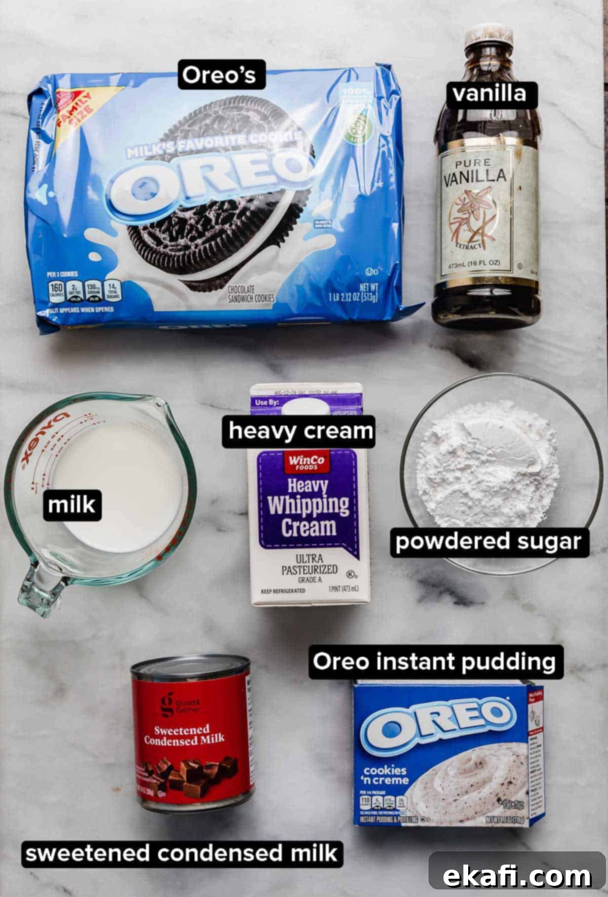 Όρεο Τρυπητό Κέικ 4 Συστατικά για επικάλυψη Oreo Poke Cake σε λευκή επιφάνεια: πακέτο μπισκότων Oreo, βανίλια, κρέμα γάλακτος, γάλα, στιγμιαία πουτίγκα Oreo, γλυκό συμπυκνωμένο γάλα και ζάχαρη άχνη.