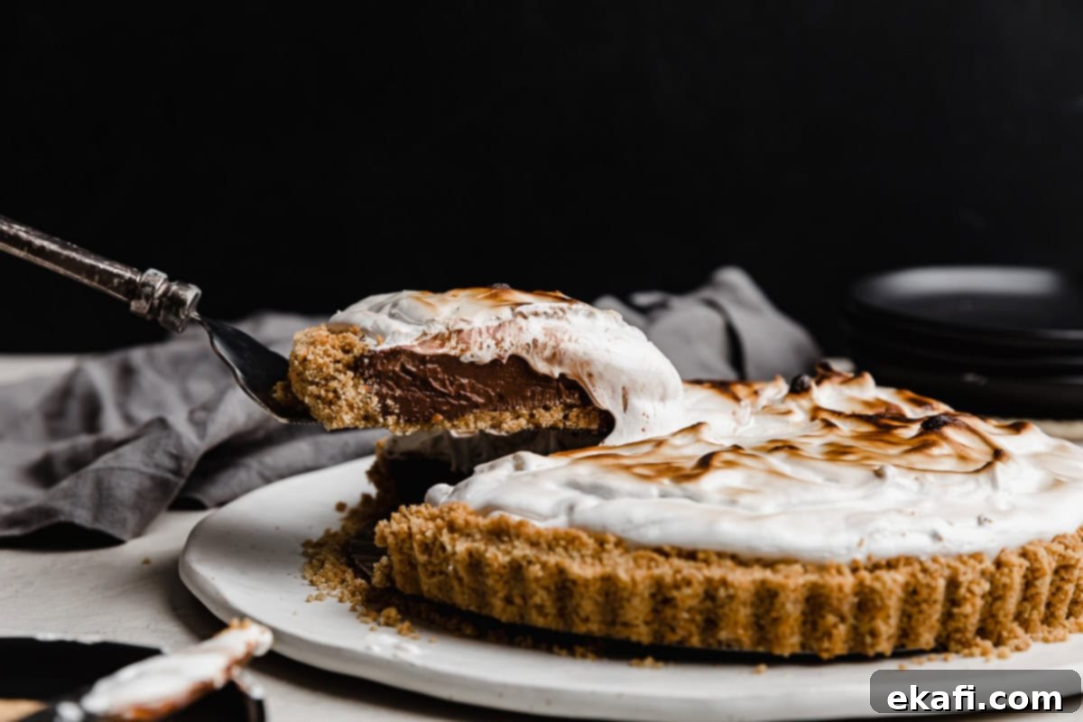 Σμόρς Τάρτα 2 Μια φέτα σπιτικής πίτας S'mores ισορροπεί σε μια σπάτουλα για πίτα, πάνω σε μαύρο φόντο.