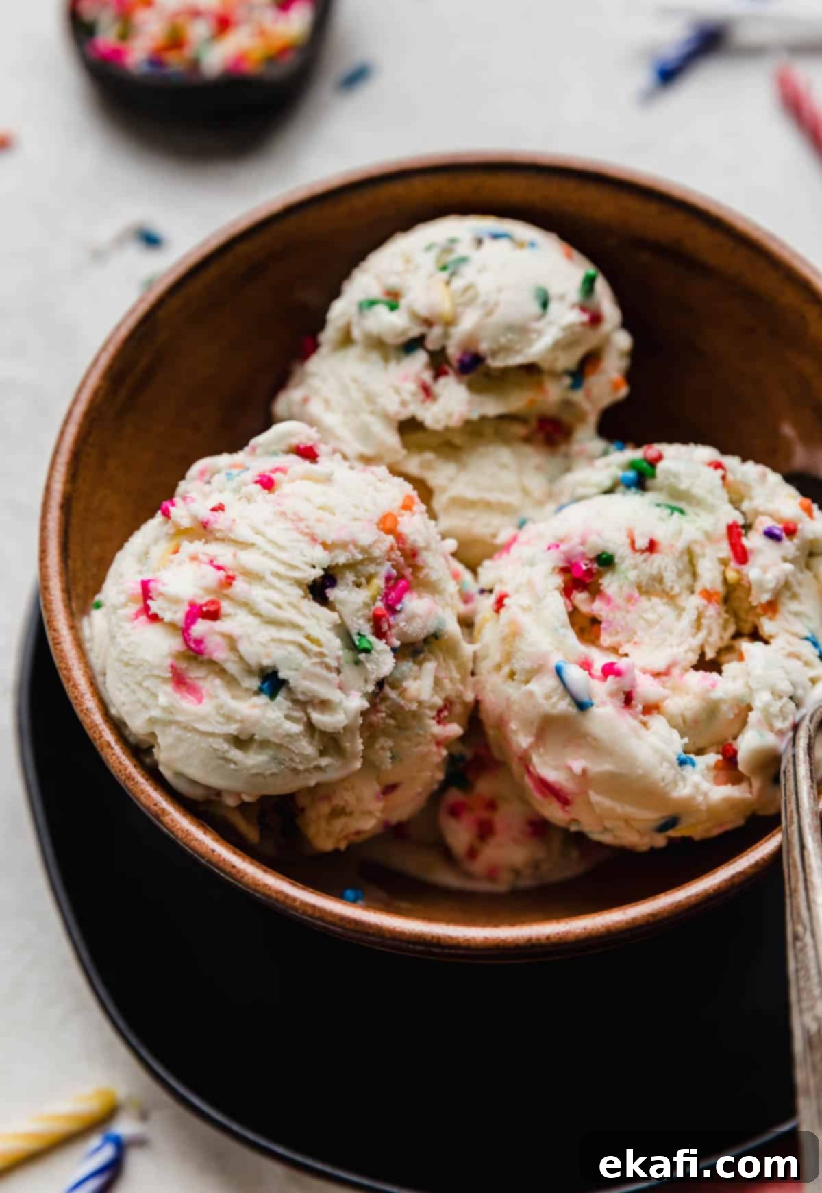 Confetti Cake Ice Cream 6 Three scoops of sprinkle loaded Birthday Cake Ice Cream in a brown bowl.