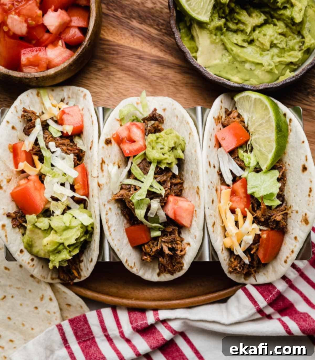 Fall-Apart Tender Slow Cooker Beef Tacos 2 Three flour tortillas filled with Crock Pot Shredded Beef Taco mix, shredded lettuce, guacamole, and tomatoes.