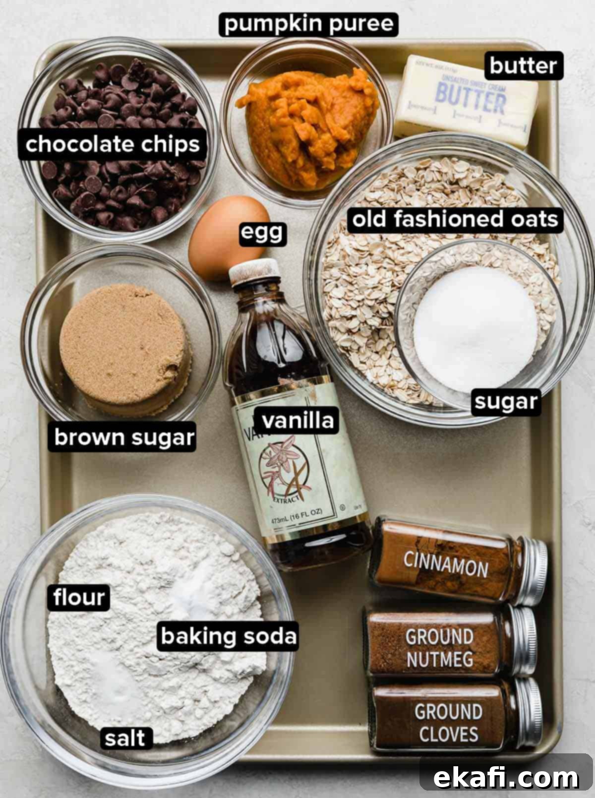 Cozy Pumpkin Chocolate Chip Oatmeal Delights 3 Chocolate Chip Oatmeal Pumpkin Cookies ingredients portioned into glass bowls on a silver baking tray, showing the various components before mixing.