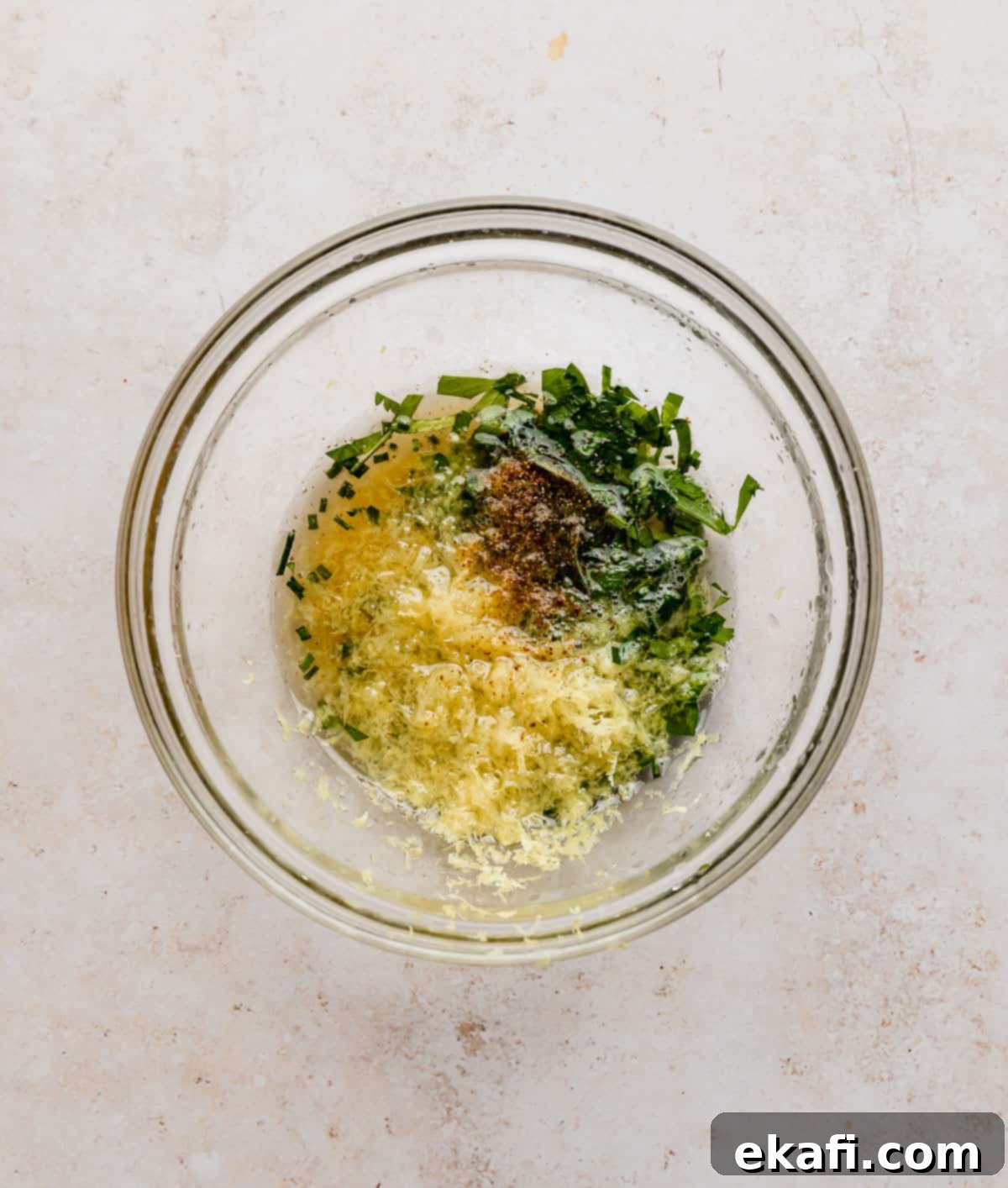 Sweet and Zesty Glazed Salmon 3 A glass bowl containing a vibrant lemon honey sauce with chopped parsley, chives, lemon zest, and lemon juice.