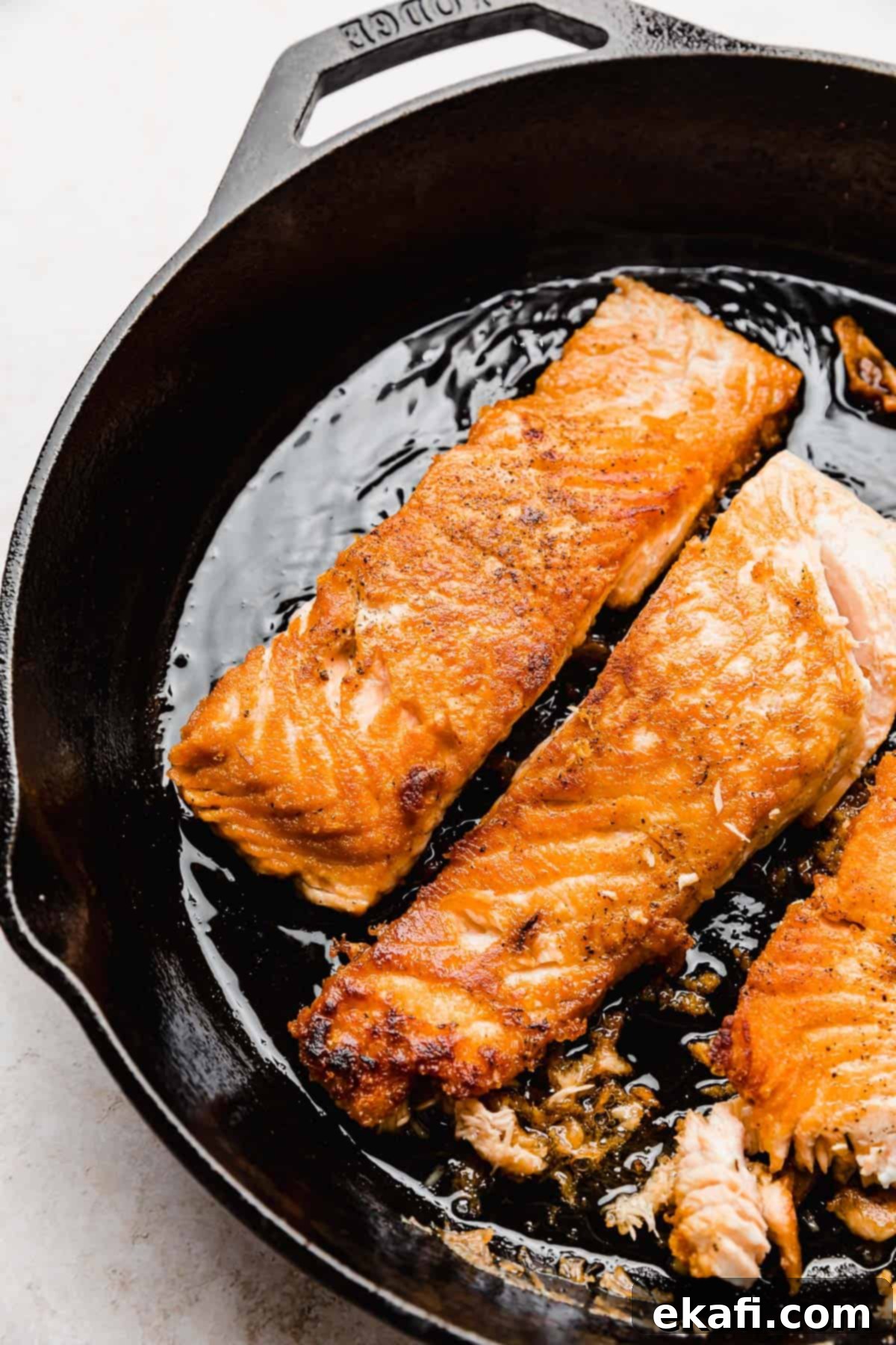 Sweet and Zesty Glazed Salmon 4 Perfectly seared Lemon Honey Glazed Salmon in a cast iron skillet, ready to serve.