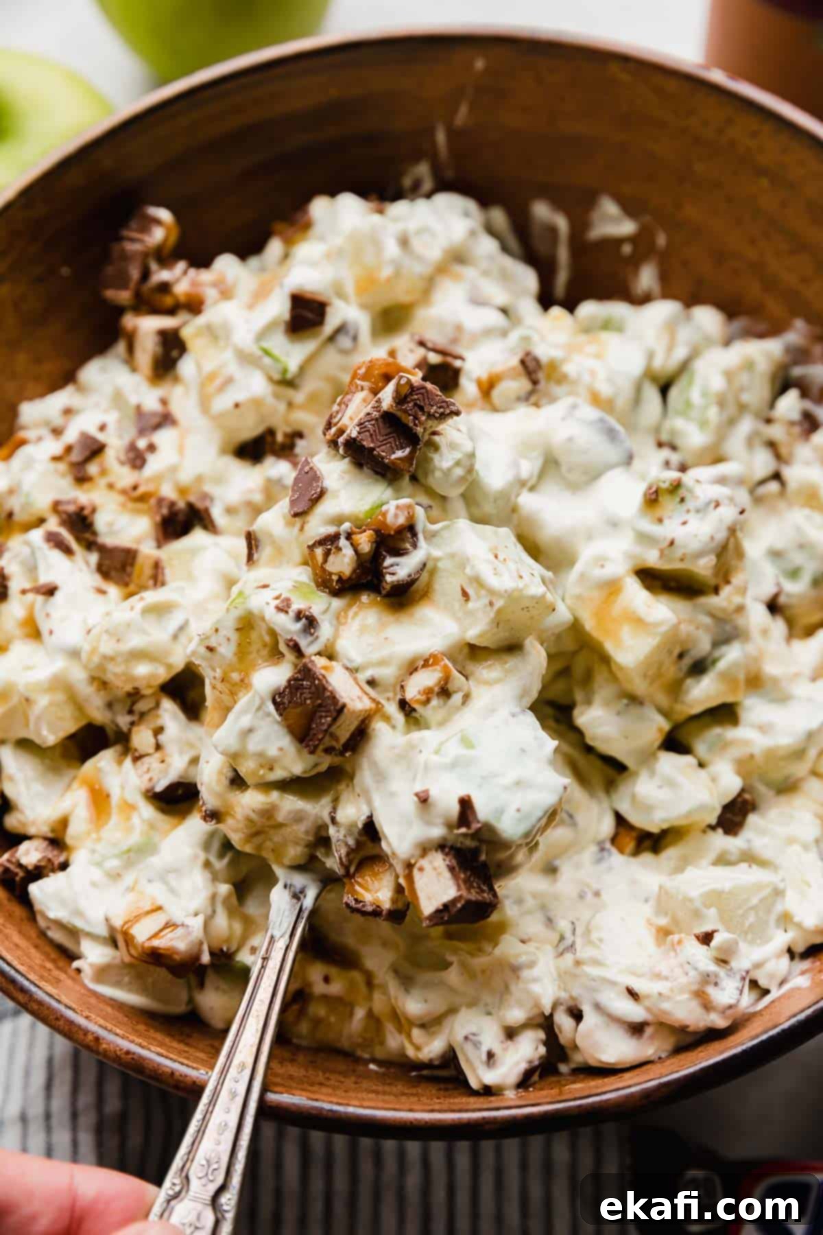 Creamy Snickers Apple Delight 6 A spoon balancing a large scoop of Apple Snickers Salad on it.