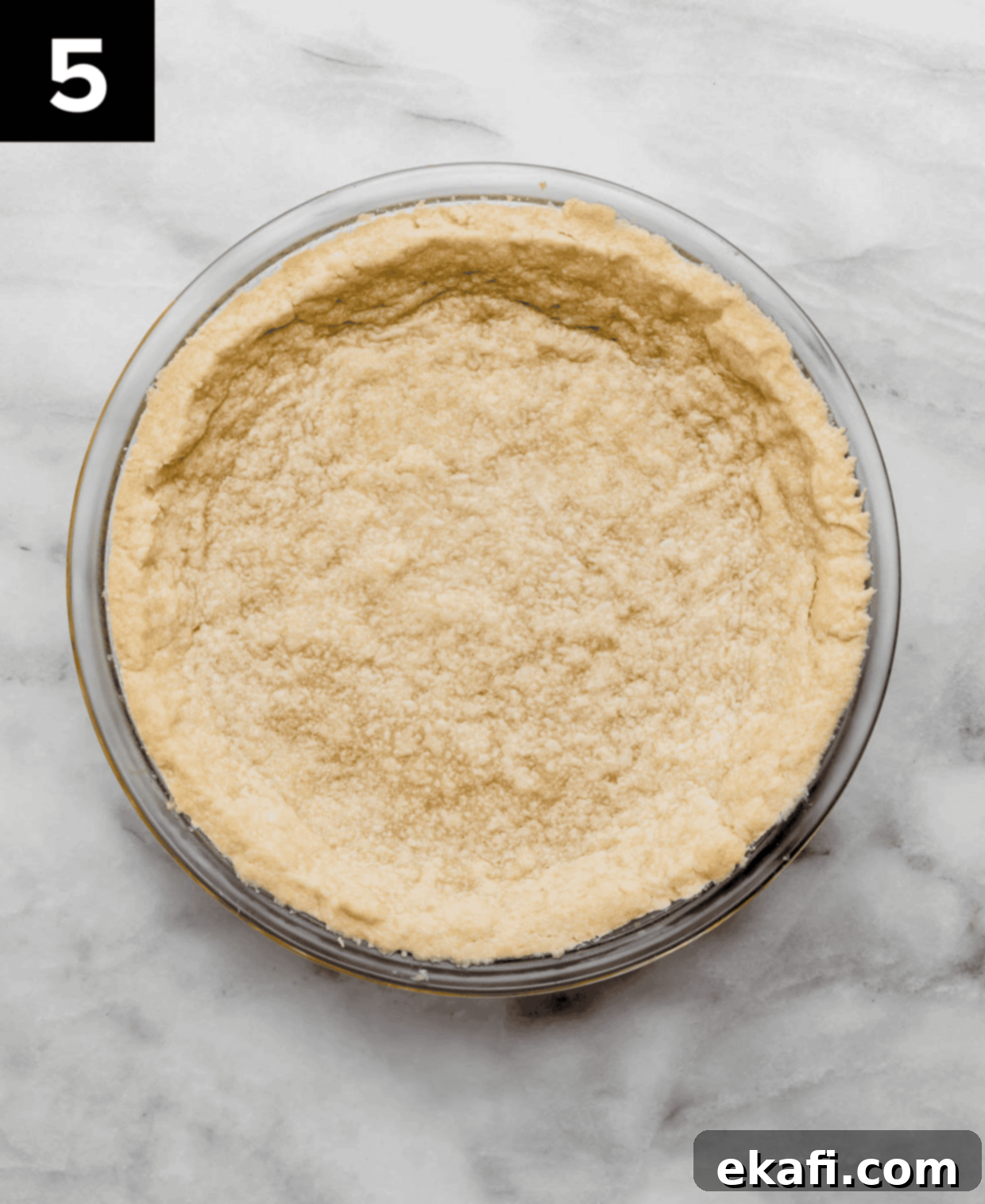 Buttery Shortbread Pie Base 5 A baked Shortbread Pie Crust in a round 9" pie plate on a white and gray marbled surface.
