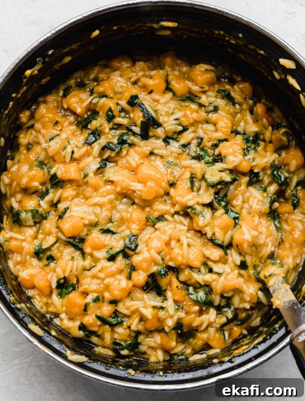 Creamy Butternut Squash Orzo 8 A black pot filled with creamy Butternut Squash Orzo pasta with kale.