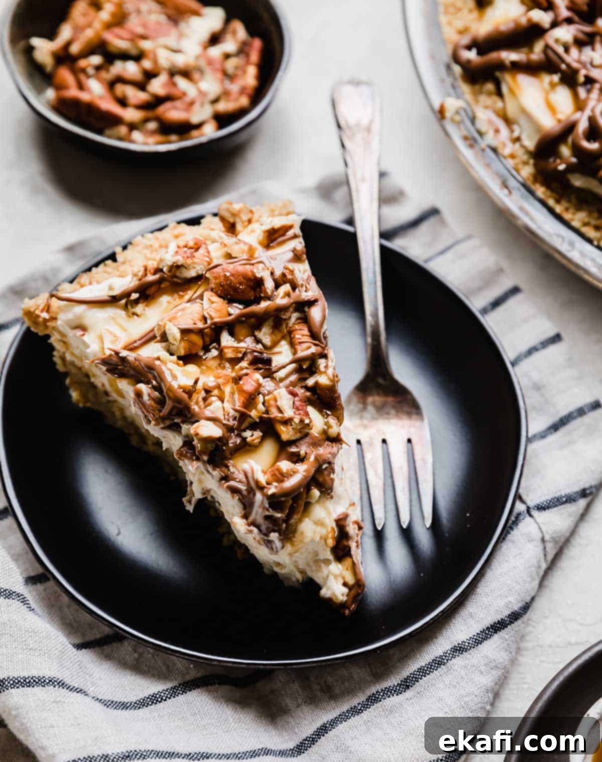 Caramel Pecan Utopia 7 A slice of cream cheese caramel turtle pie on a black plate.