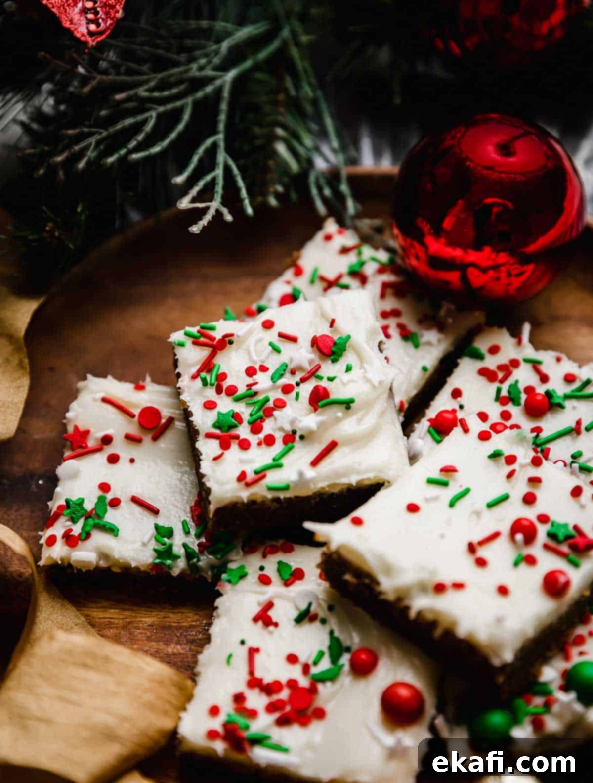 Soft & Chewy Gingerbread Bars 2 Gingerbread Cookie Bars topped with cream cheese frosting and red and green sprinkles, on a brown plate.
