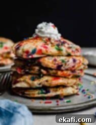 Confetti Morning Cakes 8 A stack of Birthday Cake Pancakes with whipped cream on top against a black background.