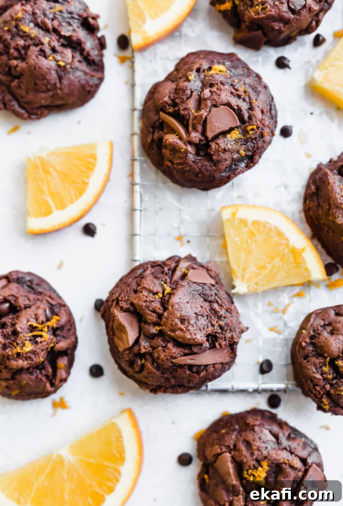 Irresistible Chocolate Orange Cookies 2 Chocolate Orange Cookies on a white background surrounded by sliced oranges.