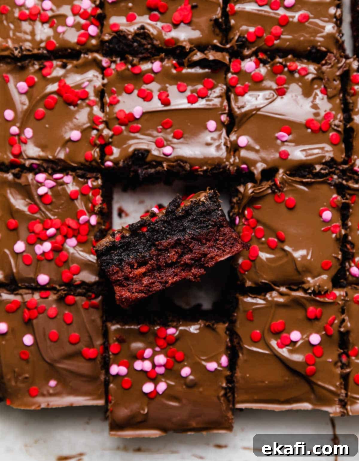 Crimson Oreo Truffle Dream Bars 2 Red Velvet Oreo Brownies topped with melted milk chocolate and pink and red sprinkles, cut into squares. A close-up view of the rich layers.
