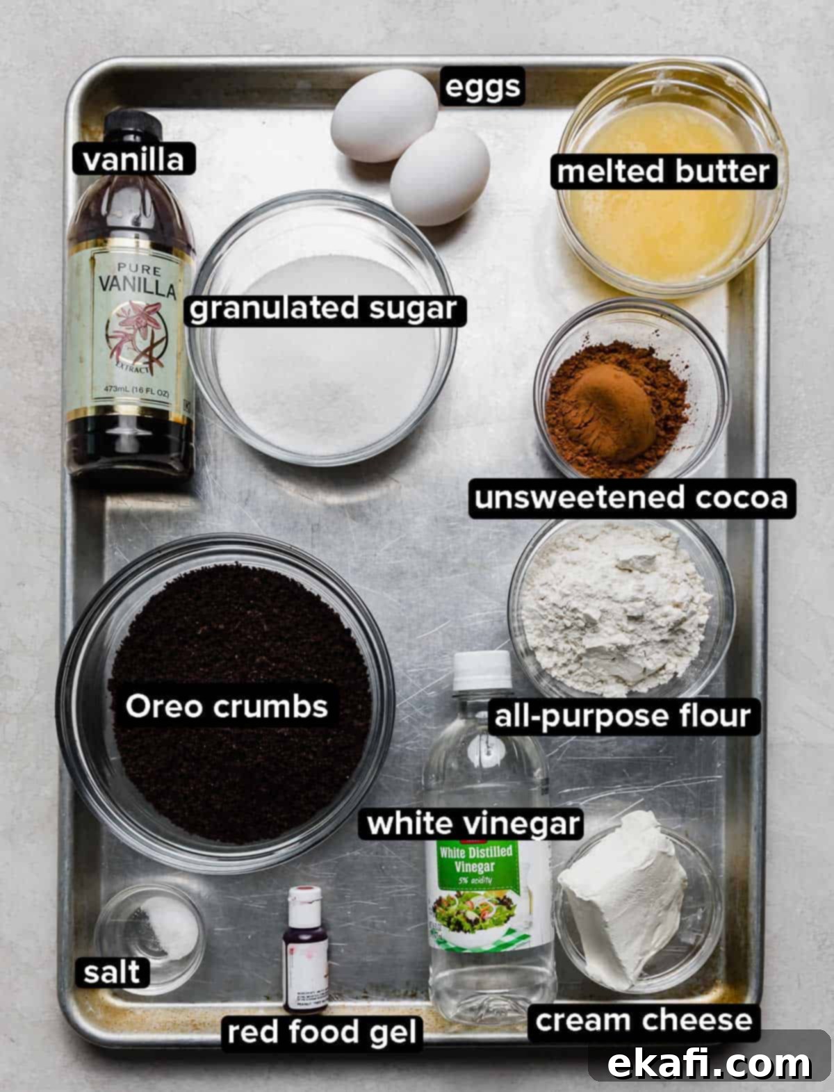 Crimson Oreo Truffle Dream Bars 3 Red Velvet Oreo Truffle Brownies ingredients portioned into glass bowls on a silver baking sheet on a white background, ready for baking.