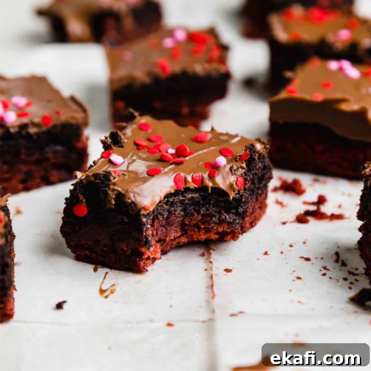Crimson Oreo Truffle Dream Bars 7 A chocolate covered red velvet brownie topped with Oreo truffle with a bite taken out of the Valentines inspired brownie, showing the rich layers.
