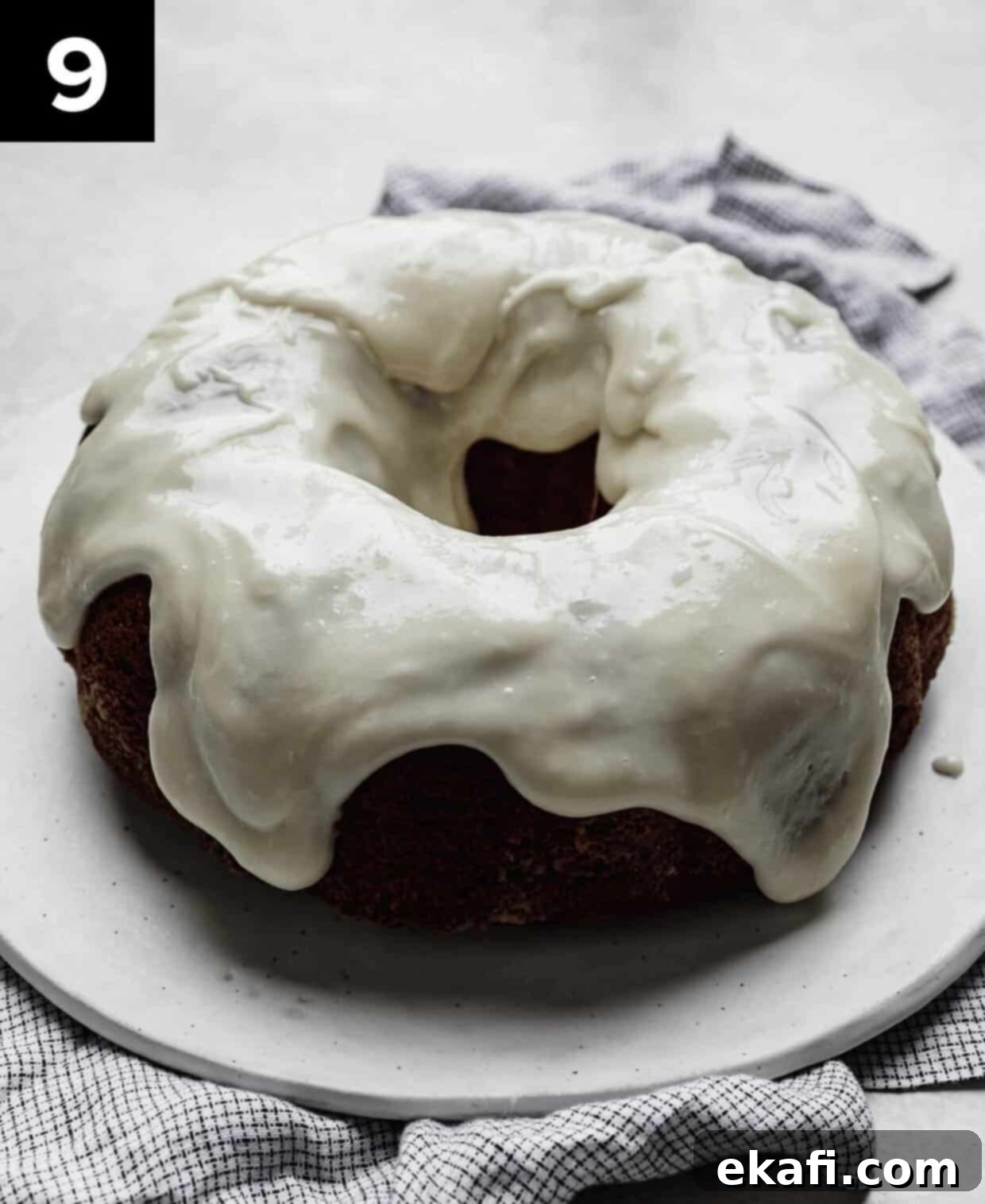 Velvety Crimson Crown 6 A beautifully cream cheese glazed Red Velvet Bundt Cake on a pristine white plate, ready to be served, showcasing the rich red hue and smooth glaze.
