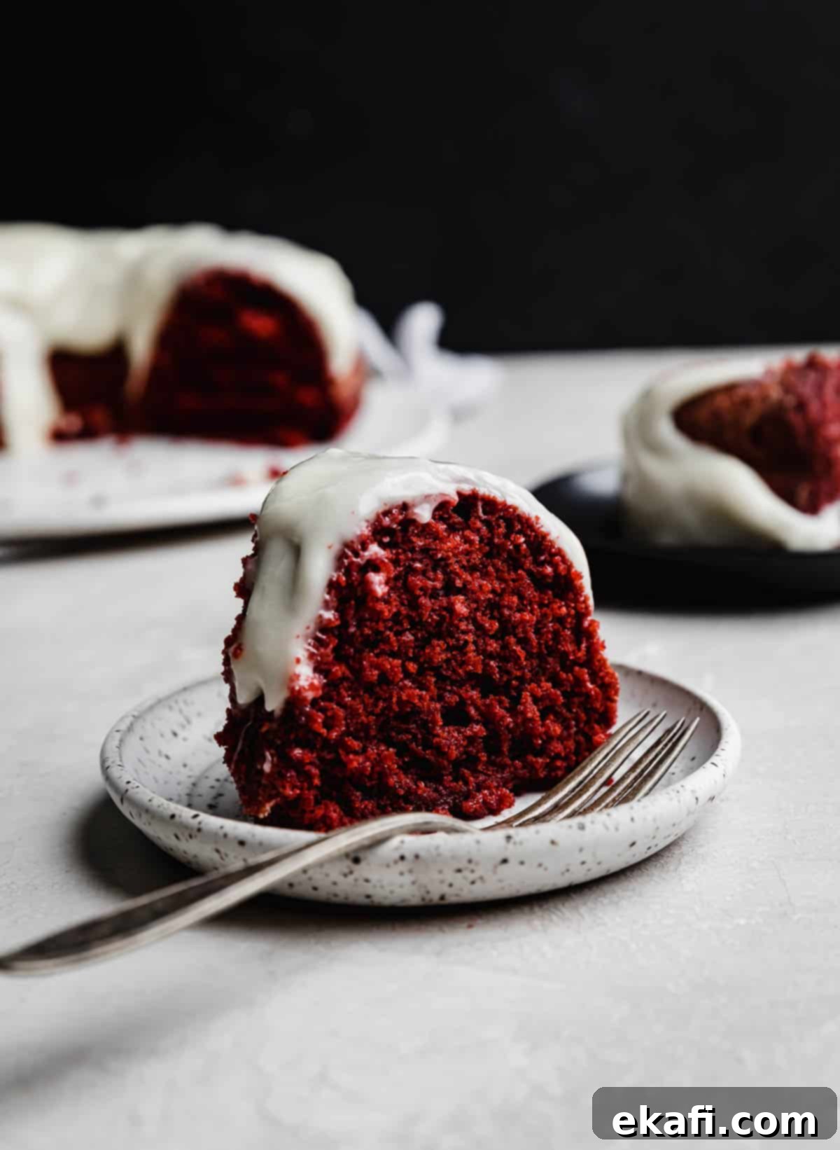 Velvety Crimson Crown 8 A perfect slice of Red Velvet Bundt Cake, showcasing its incredibly moist interior and the delicate crumb, resting on a white plate.