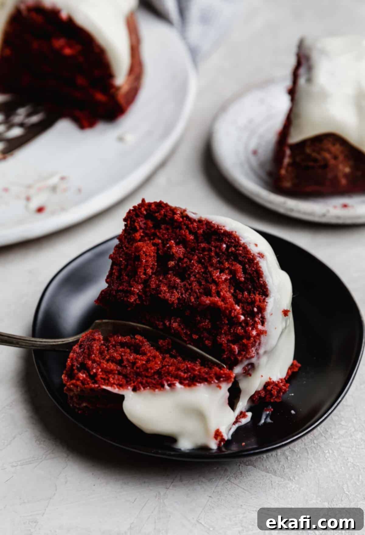 Velvety Crimson Crown 9 A delectable slice of Red Velvet Bundt Cake, beautifully glazed and placed on an elegant black plate, ready to be enjoyed.