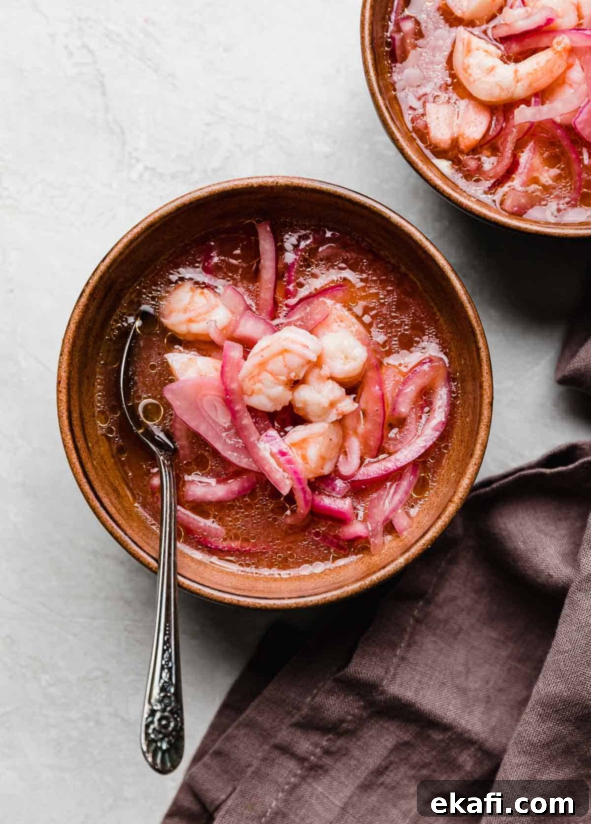 Refreshing Cooked Shrimp Ceviche 7 A traditional Shrimp Ceviche recipe in a brown bowl with a deep purple colored napkin to the right side of the bowl.