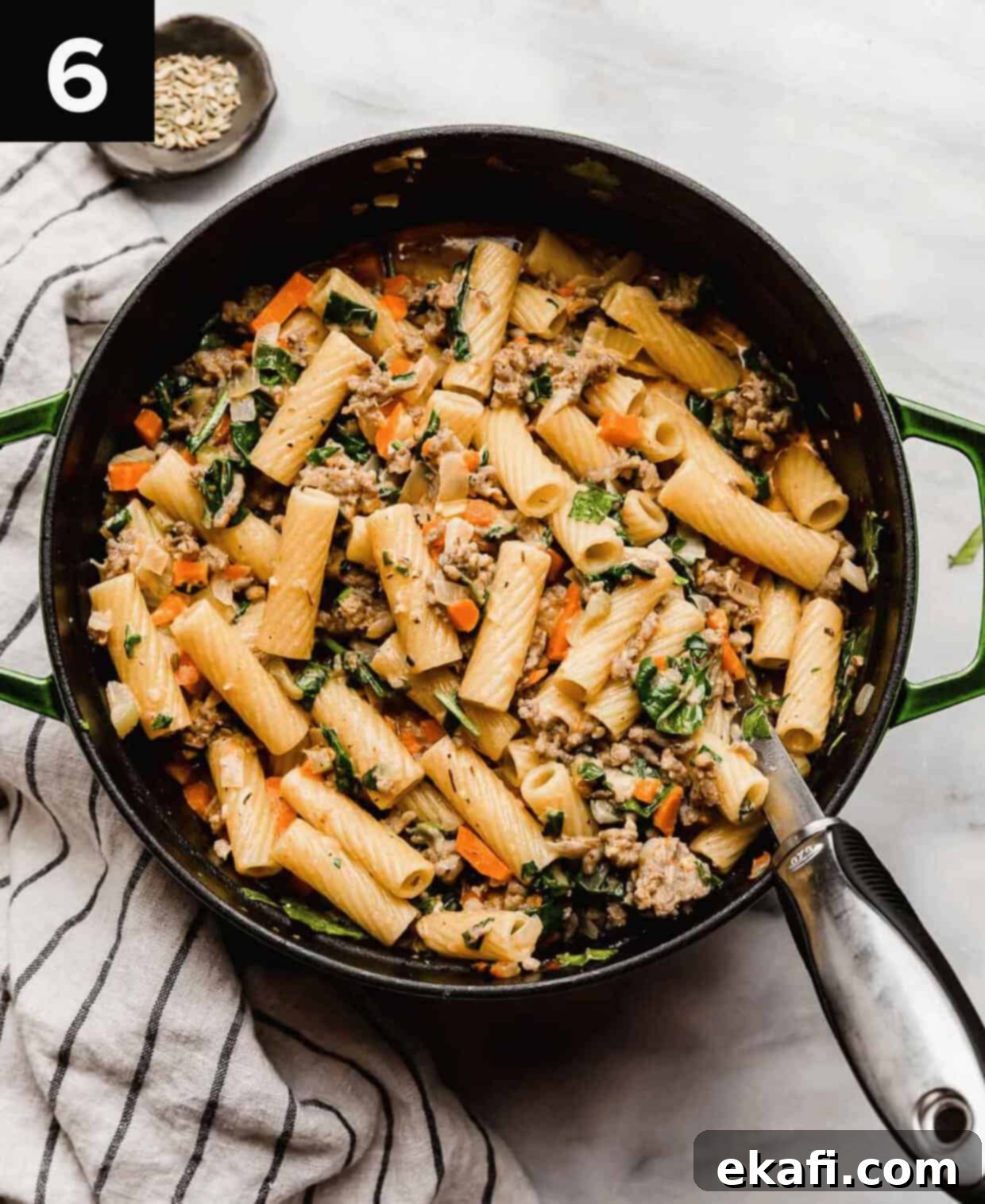 Italian Sausage Rigatoni 6 The best Italian Sausage Rigatoni recipe with spices and spinach in a large dutch oven with a large silver serving spoon in the pasta.