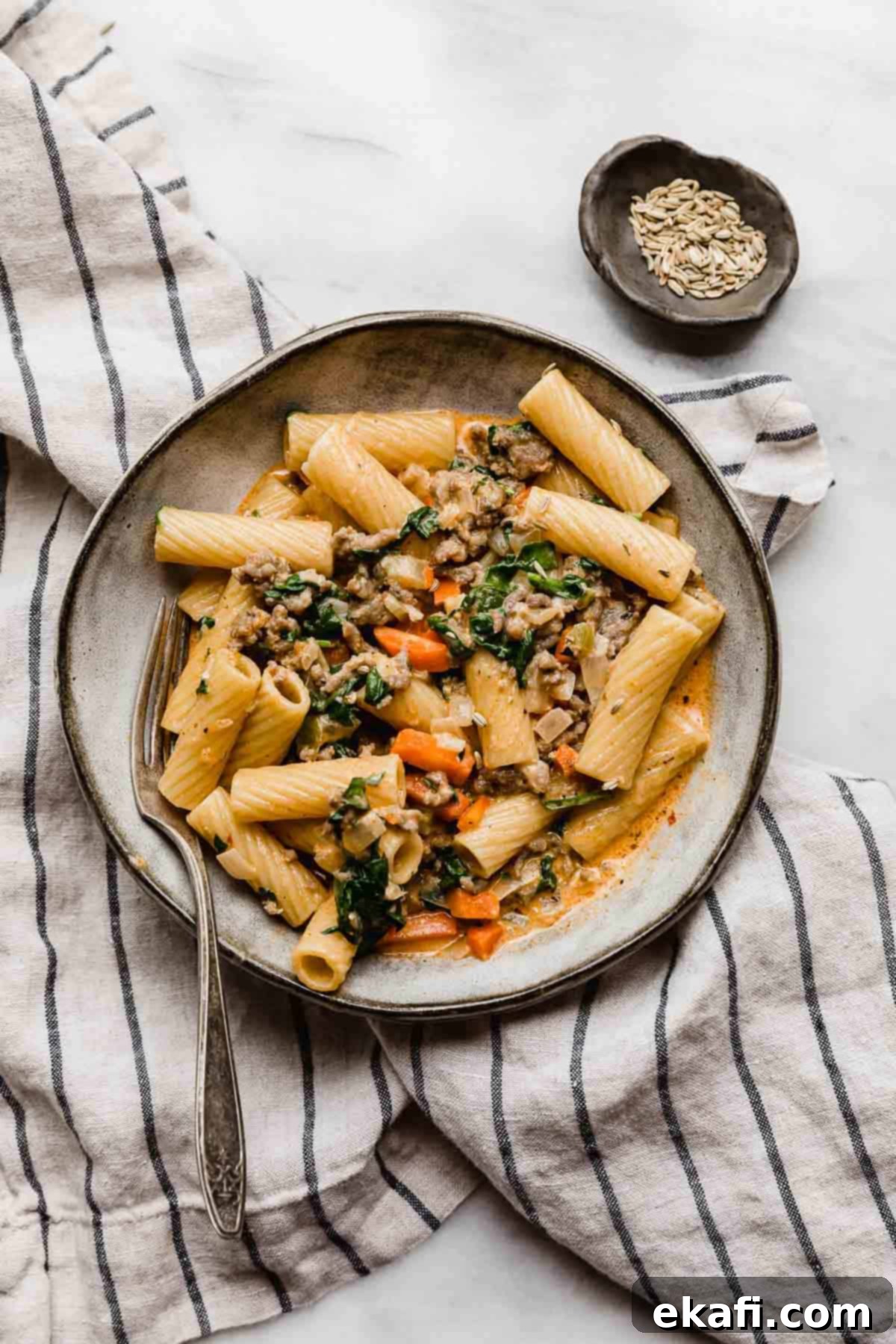 Italian Sausage Rigatoni 7 A gray pasta plate topped with the best Sausage and Rigatoni pasta recipe with carrots and spinach.