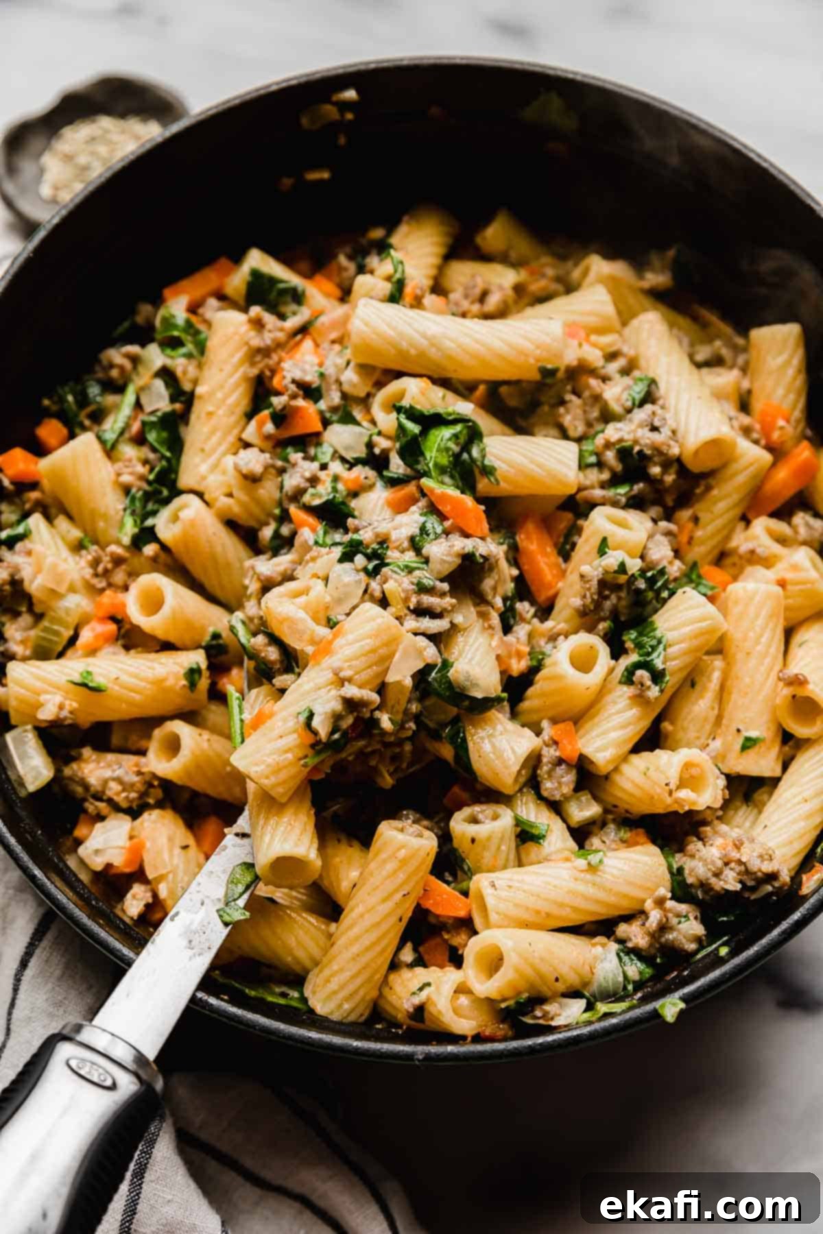 Italian Sausage Rigatoni 8 A serving spoon scooping up a portion of homemade Italian Sausage Rigatoni from a large pot.
