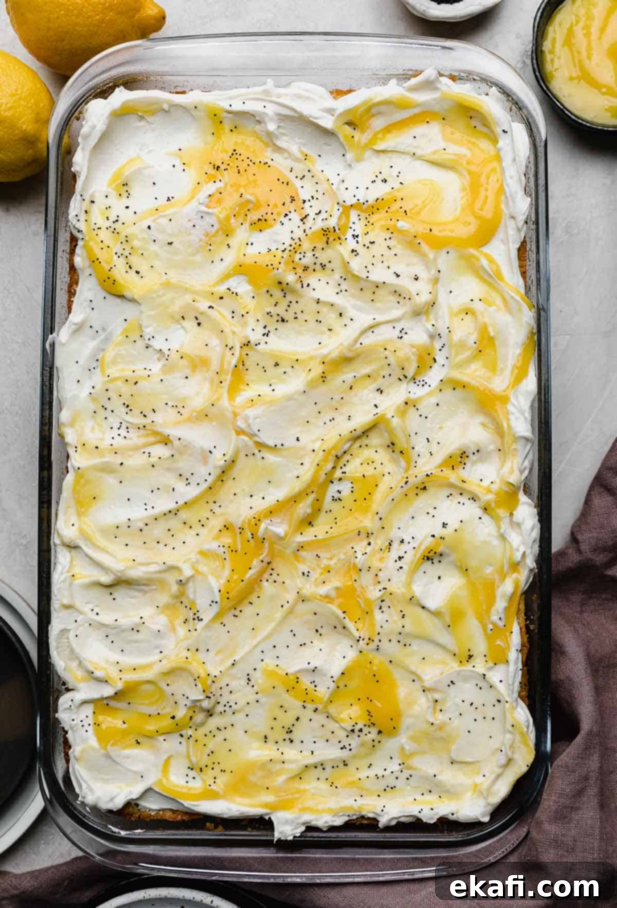 Sunshine Lemon Poppy Seed Cloud Cake 9 Overhead photo of lemon poppy seed cake topped with a whipped cream cheese frosting and dollops of homemade lemon curd on top.