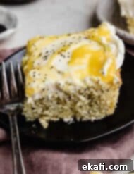 Sunshine Lemon Poppy Seed Cloud Cake 10 A slice of moist lemon poppy seed sheet cake on a black plate.