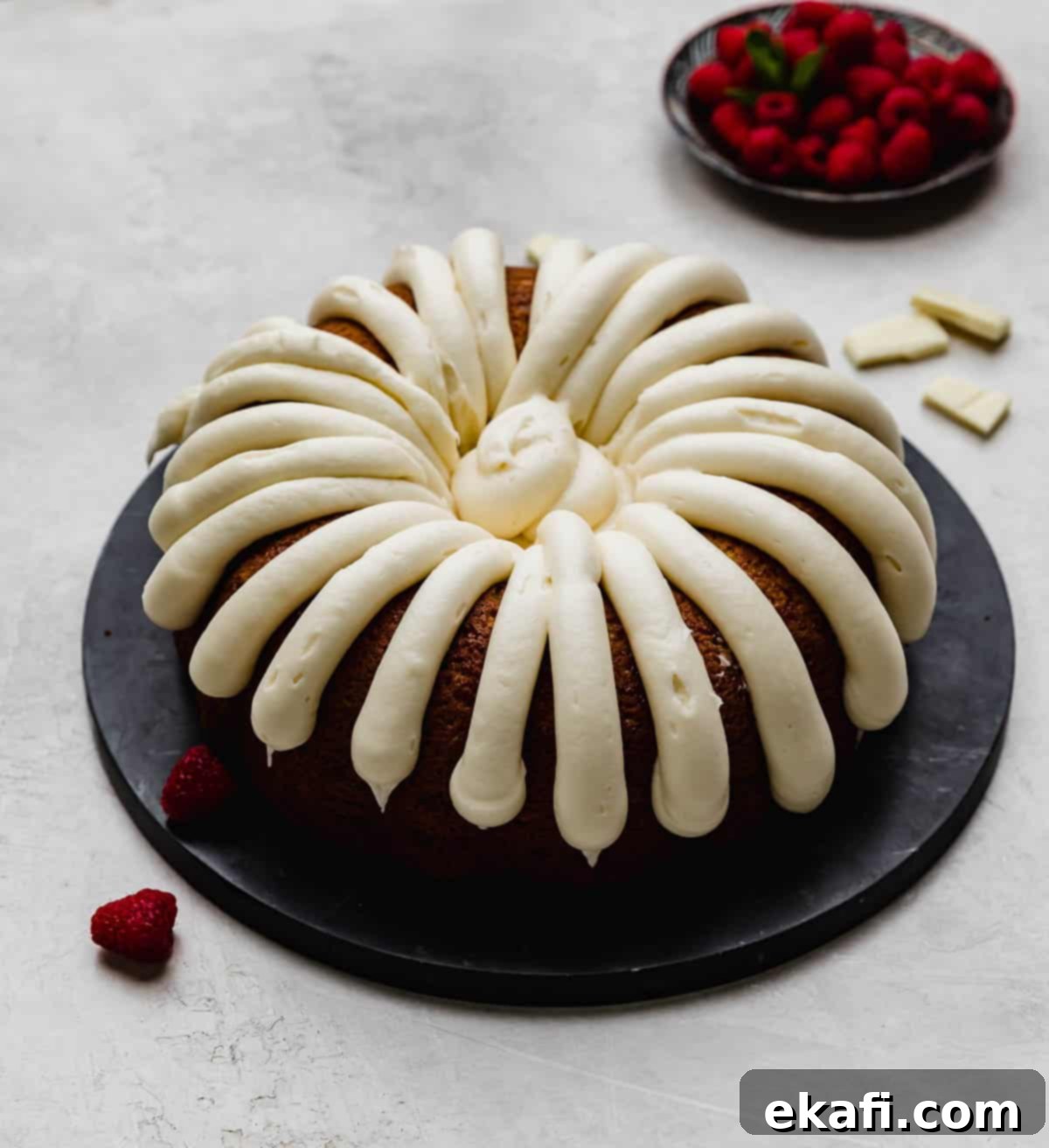 Decadent White Chocolate Raspberry Bundt Cake 2 A Nothing Bundt Cake White Chocolate Raspberry Bundt Cake copycat recipe on a black plate on a light gray background.