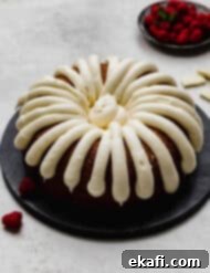 Decadent White Chocolate Raspberry Bundt Cake 9 A Nothing Bundt Cake White Chocolate Raspberry Bundt Cake copycat recipe on a black plate on a light gray background.