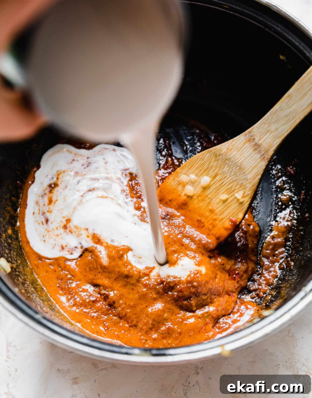 The Royal Massaman Curry 6 Coconut milk being poured into a pot with Massaman Curry paste at the bottom.