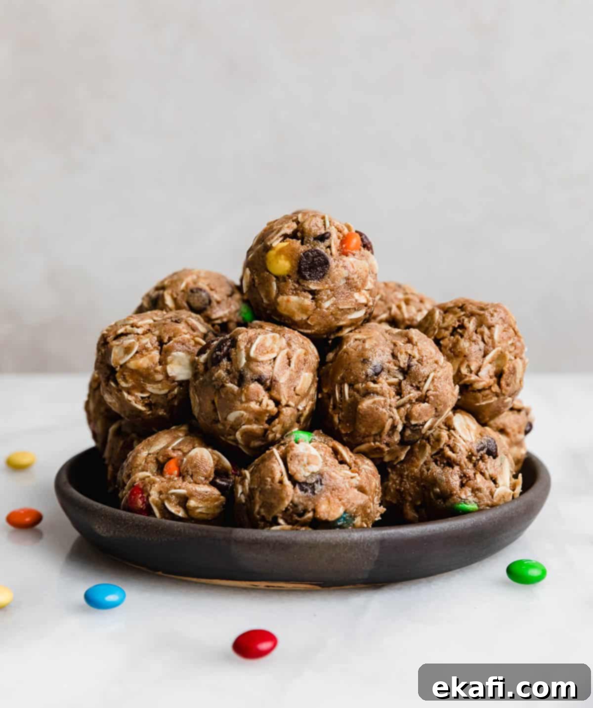 Monster Cookie Protein Bites 2 A stack of Monster Cookie Protein Balls on a black plate against a white background.