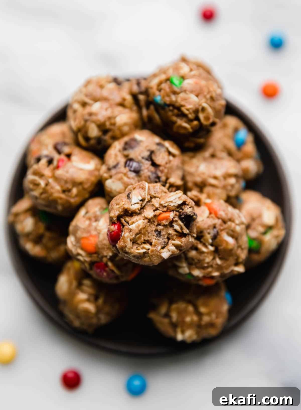 Monster Cookie Protein Bites 5 Overhead photo of Monster Cookie Protein Balls on a black plate on a white surface.