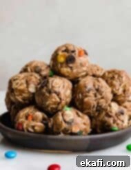 Monster Cookie Protein Bites 6 Monster Cookie Protein Balls with protein powder and M&M's on a black plate against a white background.