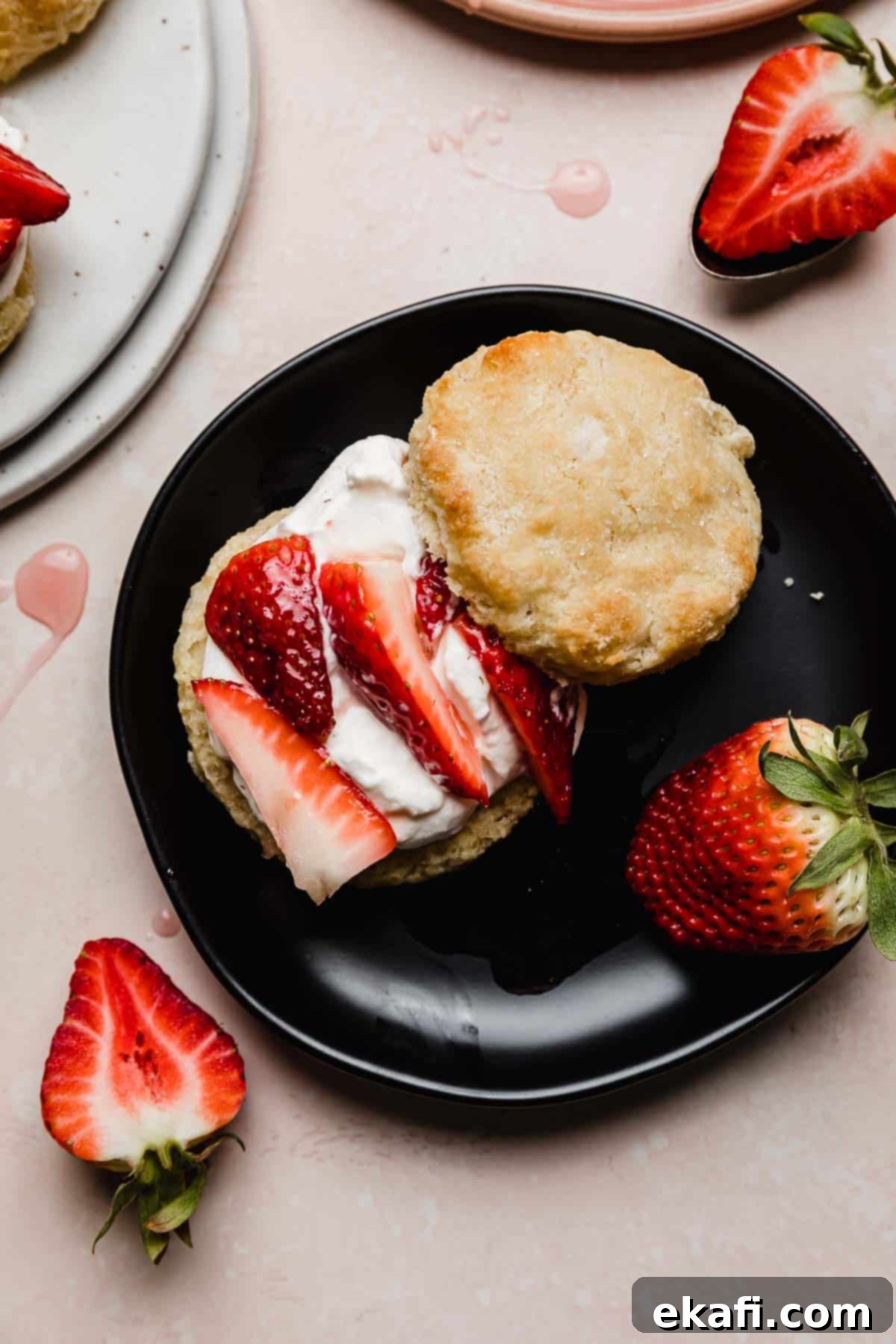 Grandma's Strawberry Shortcake 8 A biscuit topped with whipped cream, sliced strawberries on a black plate, making the best strawberry shortcake recipe ever!