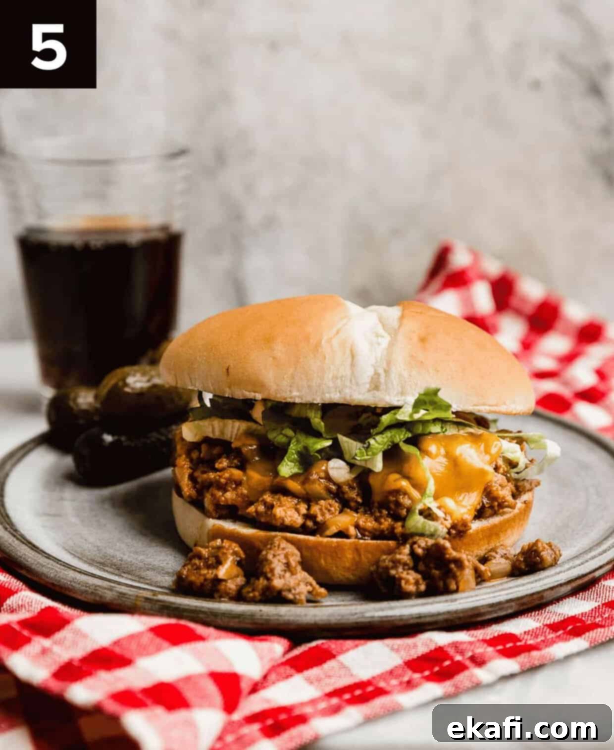 Χαμός Τυρο-Μπέργκερ 5 Ένα έτοιμο Cheeseburger Sloppy Joe σε ένα γκρι πιάτο με γκρι φόντο.