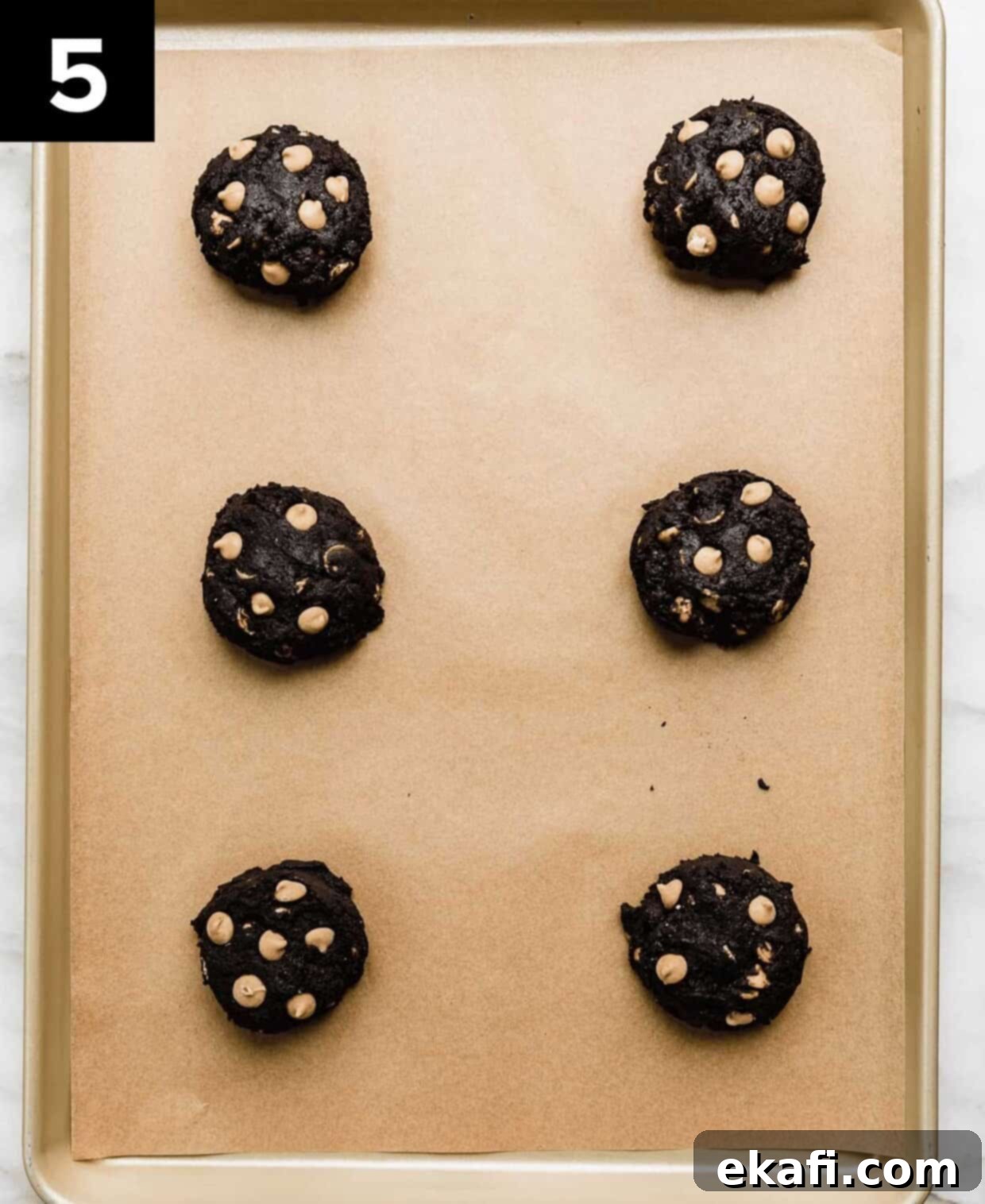 Ultimate Oreo Peanut Butter Cookies 5 Six evenly spaced, thick disks of Oreo peanut butter cookie dough on a parchment-lined baking sheet, ready for the oven.