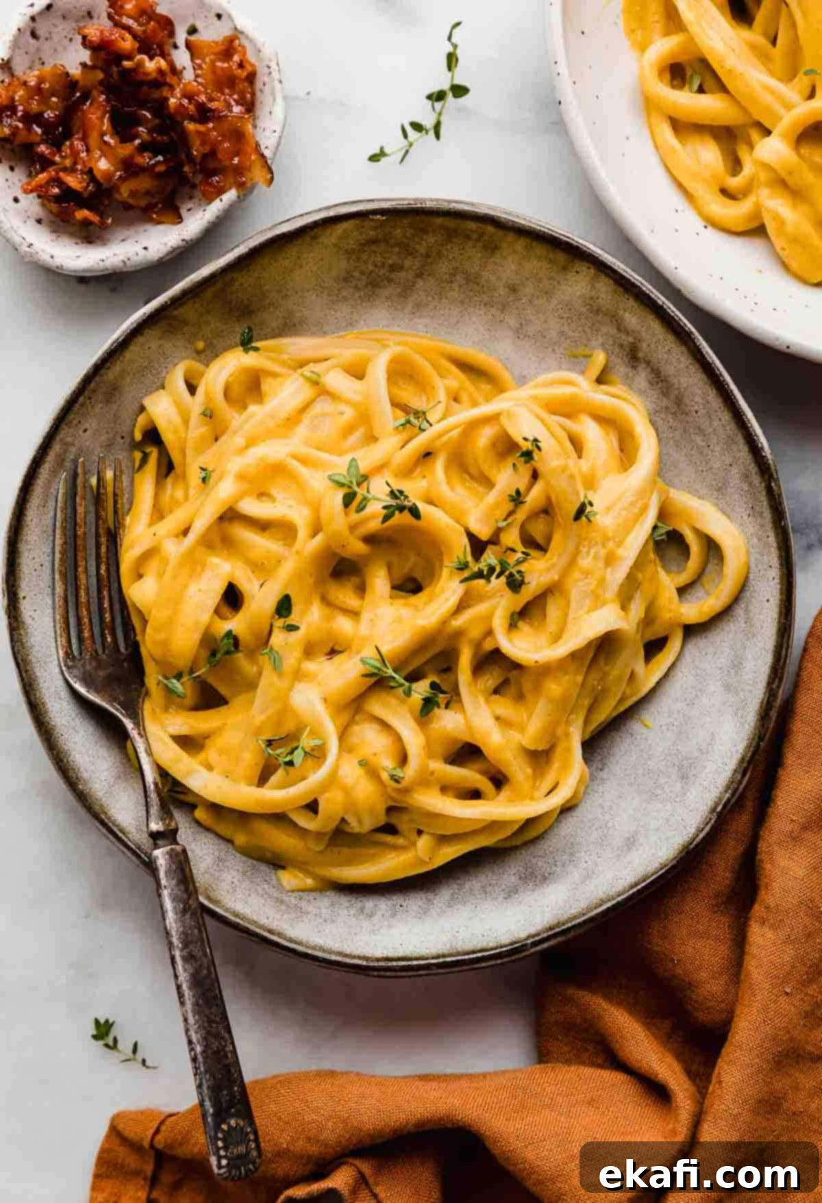 Αλφρέντο Γλυκοκολοκύθας 6 Butternut Squash Alfredo μακαρονάδα με ζυμαρικά fettuccine σε γκρι μπολ ζυμαρικών σε λευκό φόντο.