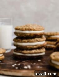 Soft Chewy Oatmeal Cream Sandwiches 8 Homemade oatmeal cream pie cookies sandwiched with white frosting against a light gray background.