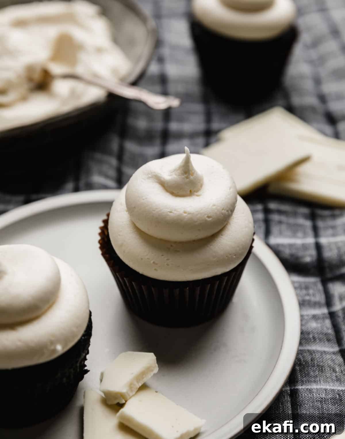 Luscious White Chocolate Frosting 2 A swirl of luscious White Chocolate Buttercream Frosting artfully piped onto a dark cupcake, highlighting its smooth texture and pristine white color.