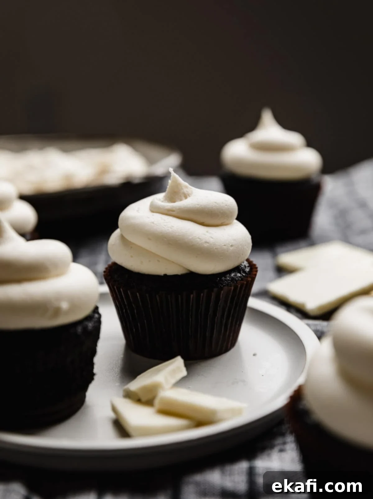 Luscious White Chocolate Frosting 6 A delectable swirl of White Chocolate Buttercream Frosting elegantly crowning a rich black velvet cupcake, ready for serving.